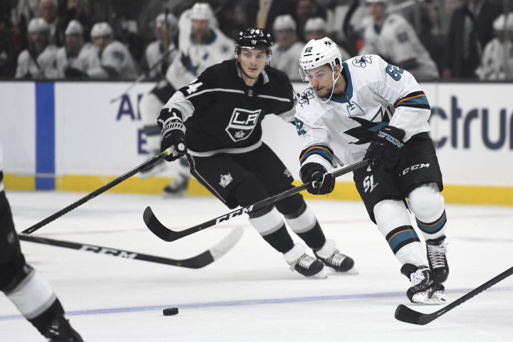 San Jose Sharks right wing Kevin Labanc, right, works his way through the Los Angeles Kings defense during the first period of an NHL hockey game, Monday, Nov. 25, 2019, in Los Angeles. (AP Photo/Michael Owen Baker)