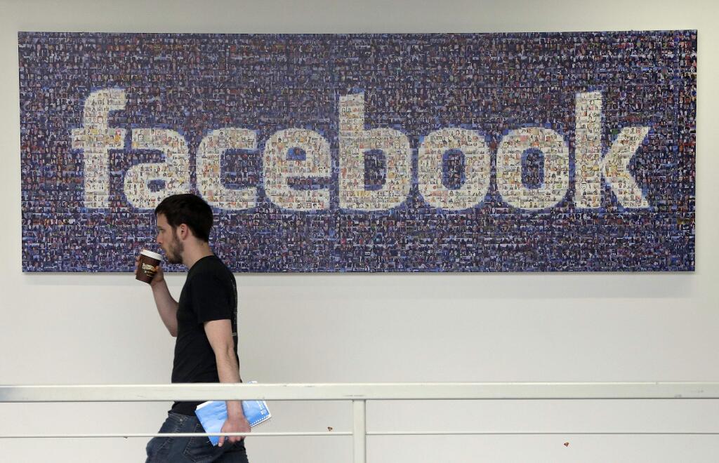 FILE - Facebook ranked #2 on Glassdoor's Best Places to Work list. In this March 15, 2013, file photo, a Facebook employee walks past a sign at company headquarters in Menlo Park, Calif. (AP Photo/Jeff Chiu, File)
