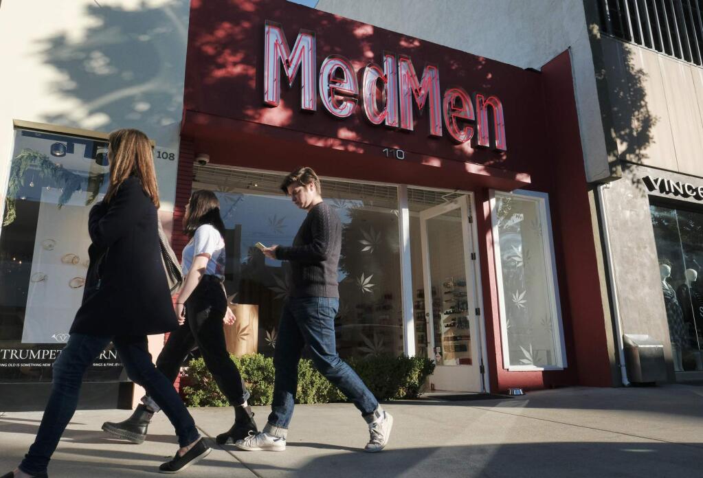 FILE - In this Thursday, Dec. 21, 2017, file photo pedestrians walk past one of the MedMen marijuana dispensaries in Los Angeles. California's struggling legal cannabis industry is expected to grow next year to $3.1 billion, but it remains far outmatched by the state's thriving illegal market. A report released Thursday, Aug. 15, 2019, finds consumers are spending roughly $3 in the state's underground pot economy for every $1 in the legal one. (AP Photo/Richard Vogel, File)