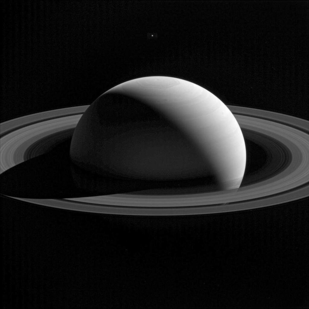 This Jan. 26, 2015 image made available by NASA shows Saturn's moon Tethys, above, behind the planet. Tethys, like all of Saturn's major moons and its ring system, orbits almost exactly in the planet's equatorial plane. (NASA/JPL-Caltech/Space Science Institute via AP)