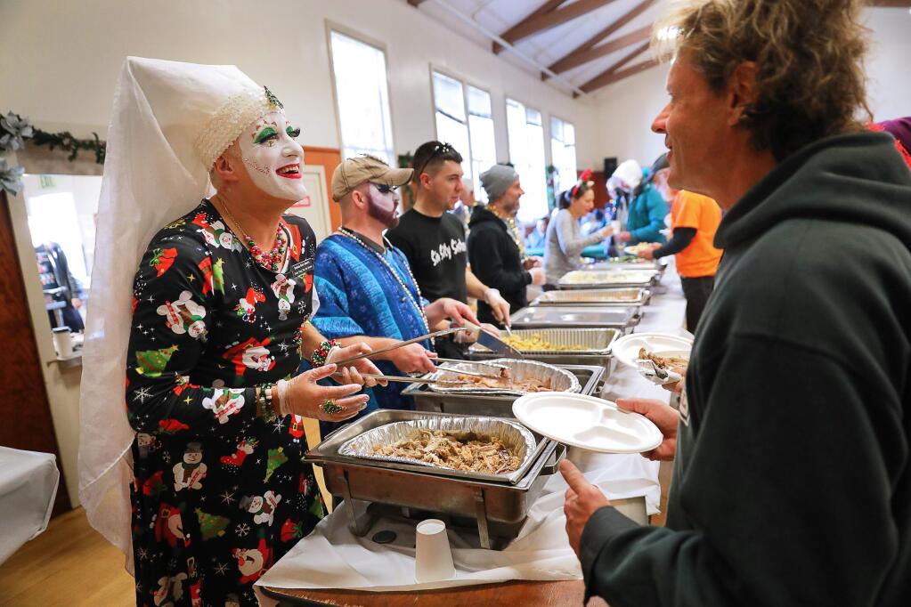 The Sisters of Perpetual Indulgence are an international street performance organization that uses drag and religious imagery to protest sexual intolerance and satirize issues of gender and morality. The Russian River chapter is involved in charitable works throughout the community. In this photo, Sister Tooty Too Too Sweet, left, and Sister Wilma Titzgro serve Christmas dinner to the needy in Guerneville on Tuesday, Dec. 25, 2018. (CHRISTOPHER CHUNG/THE PRESS DEMOCRAT)