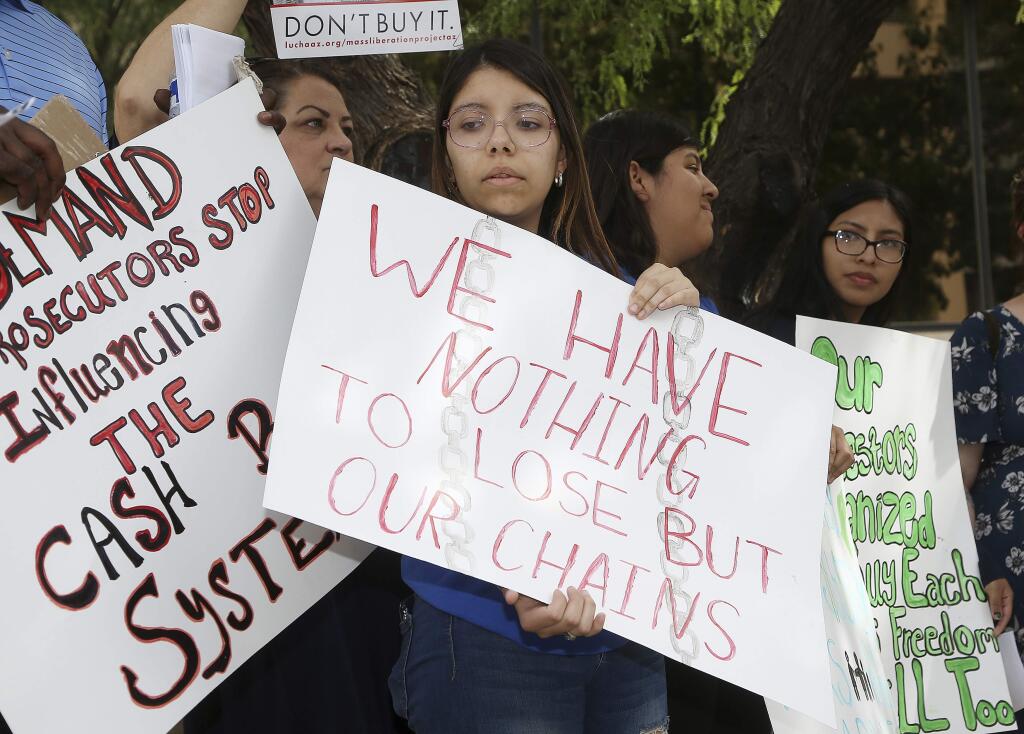 Annette Alvarez, middle, joins other protesters as they gather in front of Maricopa County Attorney Bill Montgomery's office Thursday, May 9, 2019, in Phoenix. For Mother's Day, dozens of mothers are getting time with their children instead of time behind bars as the National Bail Out Collective is organizing its 'Black Mama's Bail Out' initiative to post bail for women of color who would otherwise be in jail. (AP Photo/Ross D. Franklin)