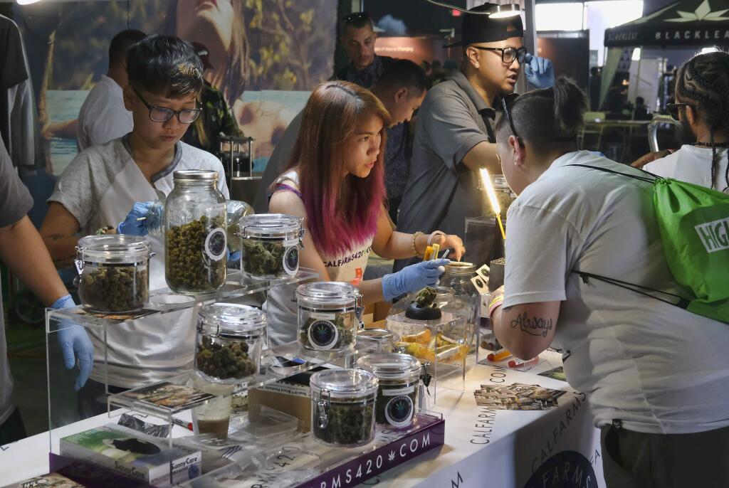 FILE - In this April 23, 2017 file photo Calfarms, a medical marijuana provider help attendees at the High Times Cannabis Cup in San Bernardino, Calif. California is trying to get control of its unruly medical marijuana industry. California would set standards for organic marijuana, allow pot samples at county fairs and permit home deliveries under legislation set to be considered by state lawmakers. The provisions were tucked into the state budget agreement between Gov. Jerry Brown and top Democratic lawmakers. It's scheduled for approval in the Legislature on Thursday, June 15, 2017. (AP Photo/Richard Vogel, File)