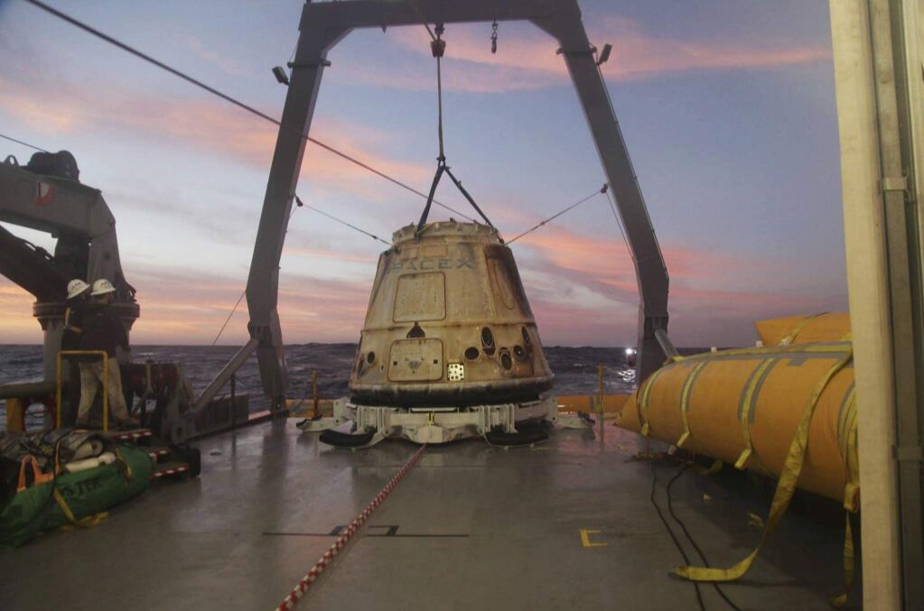 FILE - In this Tuesday, Feb. 10, 2015 file photo made available by SpaceX, their Dragon capsule sits aboard a ship in the Pacific Ocean west of Mexico's Baja Peninsula after returning from the International Space Station, carrying about 3,700 lbs of cargo for NASA. SpaceX announced Monday, Feb. 27, 2017 that it would send two paying customers to the moon next year on a private flight aboard its Dragon capsule. The company said the unnamed customers have paid “a significant deposit” for the moon trip.(AP Photo/SpaceX, File)