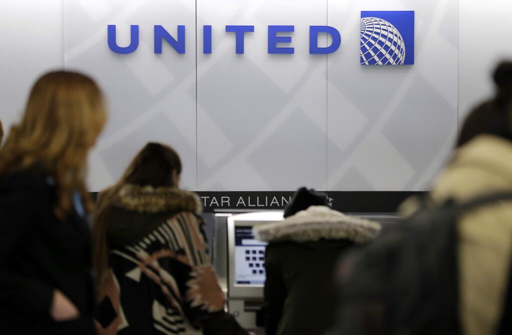 FILE- In this March 15, 2017, photo, people stand in line at a United Airlines counter at LaGuardia Airport in New York. A dog died on a United Airlines plane after a flight attendant ordered its owner to put the animal in the plane's overhead bin. United said Tuesday, March 13, 2018, that it took full responsibility for the incident on the Monday night flight from Houston to New York. (AP Photo/Seth Wenig, File)