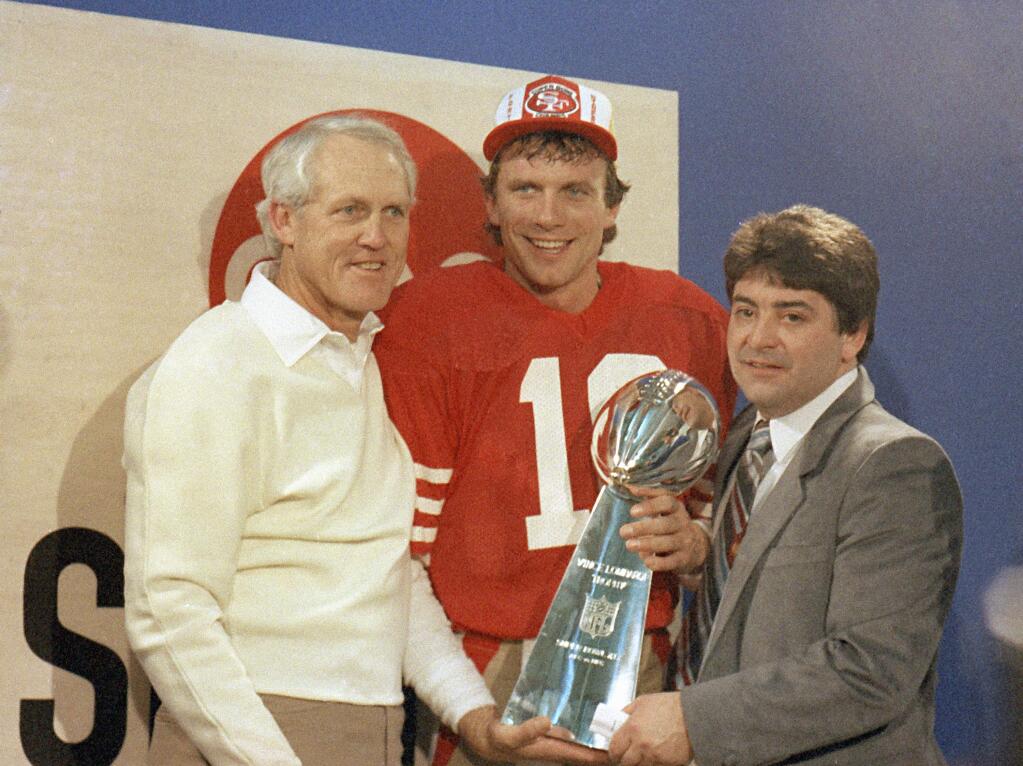 San Francisco 49ers quarterback Joe Montana, center, is shown holding the Lombardi Super Bowl trophy with coach Bill Walsh, left, and 49ers' owner Edward DeBartolo, Jr., in the locker room Jan. 20, 1985. (AP Photo)