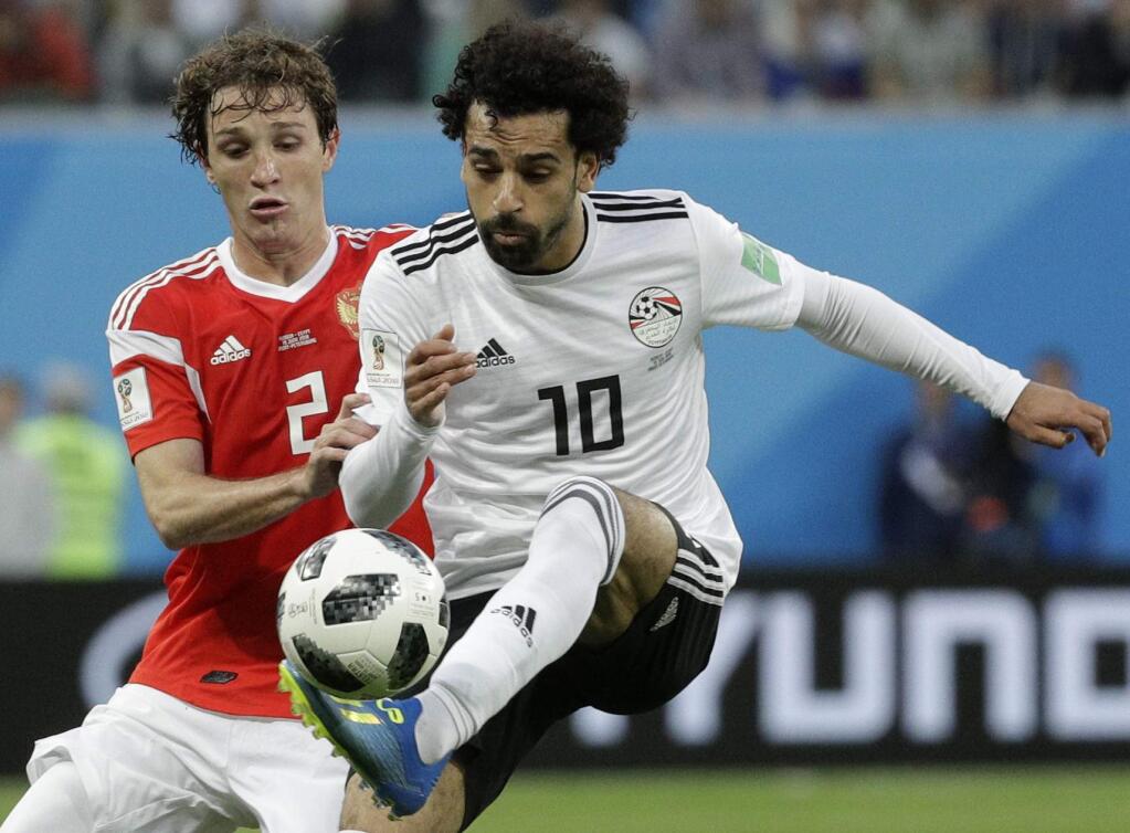 Russia's Mario Fernandes, left, challenges for the ball Egypt's Mohamed Salah, right, during the group A match between Russia and Egypt at the 2018 soccer World Cup in the St. Petersburg stadium in St. Petersburg, Russia, Tuesday, June 19, 2018. (AP Photo/Gregorio Borgia)