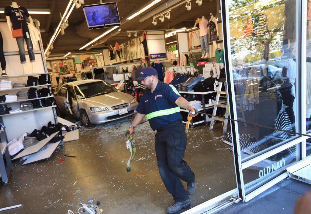 At the Old Navy store in the Santa Rosa Marketplace, Monday, April 30, 2018, Steve Manabe of Extreme Towing pulls cable to hook up a vehicle that was driven through the front doors accidentally, injuring one person. (Kent Porter / The Press Democrat) 2018