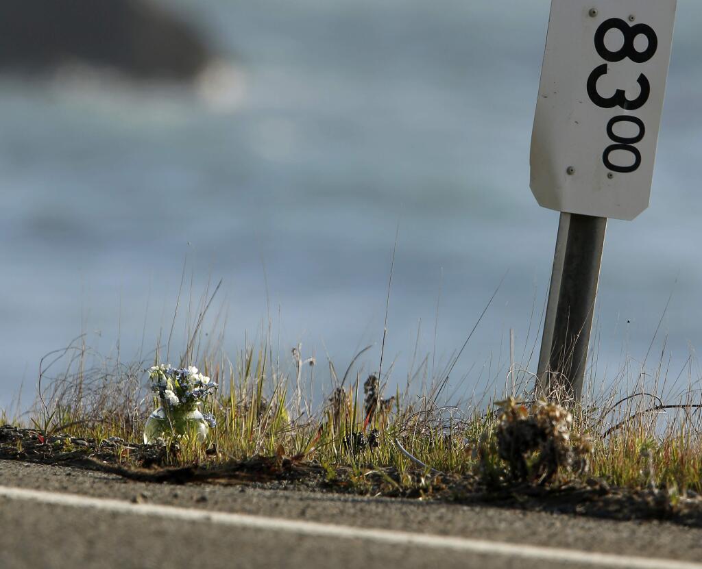 A small vase of flowers, at left, sits beside a mile marker Wednesday, March 28, 2018, near the pullout where the SUV of Jennifer and Sarah Hart was recovered off the Pacific Coast Highway near Westport, Calif. (Alvin Jornada/ PD)