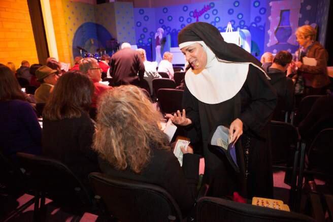 Actress Janine LaForge sells a bingo board to a theatergoer attending the opening night of the play 'Nunsense' which was also the grand opening of the Raven Theater Windsor in 2014. The theater announced it will close in December on Wednesday, Sept. 30, 2015. (CHARLIE GESELL/ FOR THE PD)