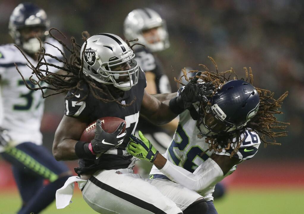 Oakland Raiders wide receiver Dwayne Harris (17), left, is challenged by Seattle Seahawks cornerback Shaquill Griffin (26) during the first half of an NFL football game at Wembley stadium in London, Sunday, Oct. 14, 2018. (AP Photo/Tim Ireland)