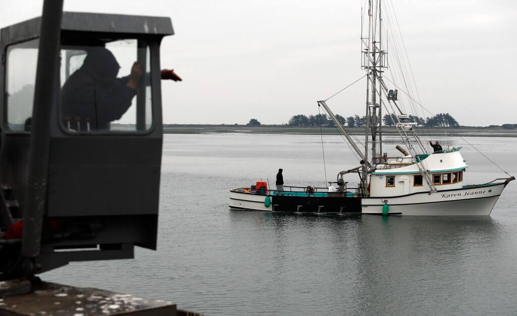 Tides Wharf dockworker Jesus Ruiz, left, motions for fishing boat captain Dick Ogg to pilot the Karen Jeanne into dock so they can offload their catch of Dungeness crab at the Tides Wharf in Bodega Bay, California, on Thursday, December 20, 2018. (Alvin Jornada / The Press Democrat)