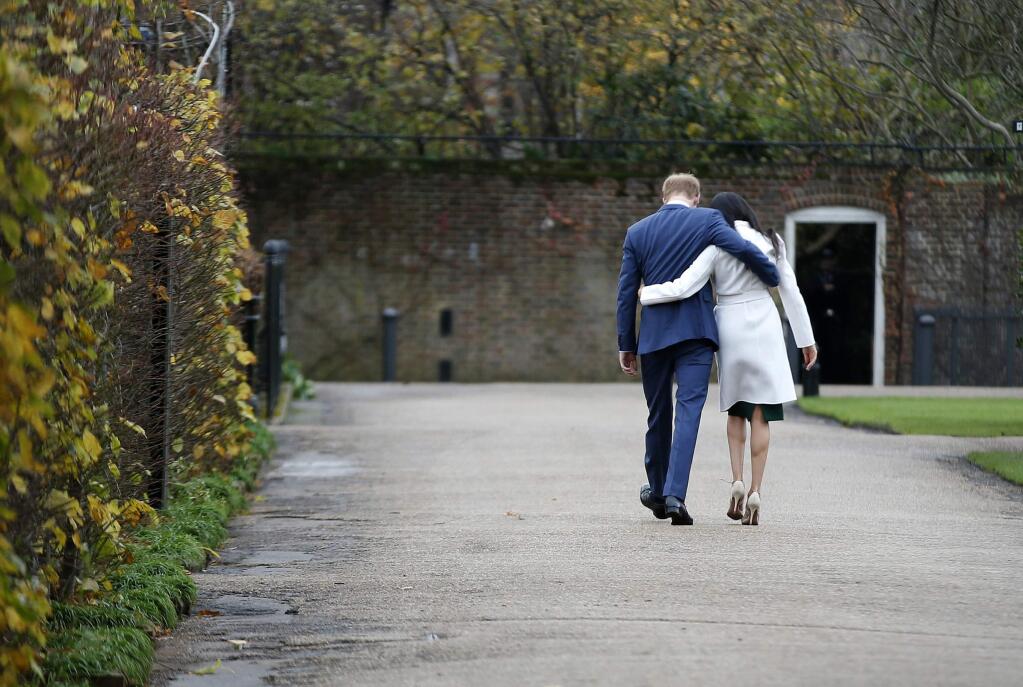 Britain's Prince Harry and Meghan Markle walk away after posing for the media in the grounds of Kensington Palace in London, Monday Nov. 27, 2017. It was announced Monday that Prince Harry, fifth in line for the British throne, will marry American actress Meghan Markle in the spring, confirming months of rumors. (AP Photo/Alastair Grant)