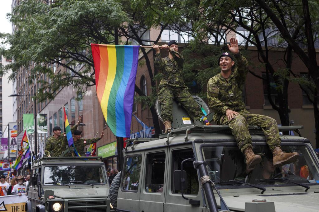 Members of the Canadian military wave a Pride flag atop a military vehicle during the Toronto Pride parade in Toronto, Sunday, June 24, 2018. (Cole Burston/The Canadian Press via AP)