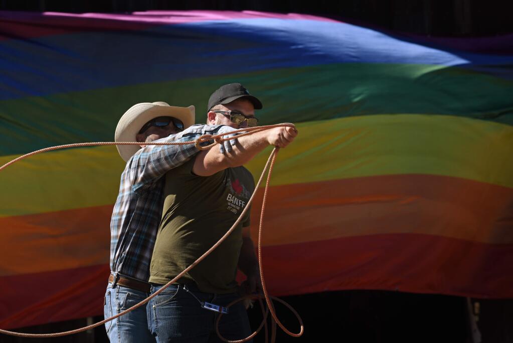 Bob Buenfil, of Los Angeles showing Jared Jiaconi, of San Francisco how to use a lasso during the Best Buck in the Bay LGBTQ rodeo held Sunday in Duncan Mills, California. September 15, 2019.(Photo: Erik Castro/for The Press Democrat)
