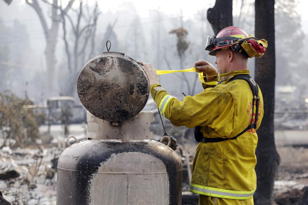 Fire Capt. Roger Lutz tags a leaking gas tank in the remains of a Middletown home destroyed in the Valley fire. (ELAINE THOMPSON / Associated Press)