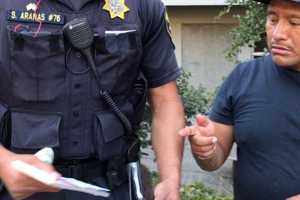 An image taken from video showing a Berkeley police officer taking money from the wallet of a hot dog vendor who had been cited for illegal sales.