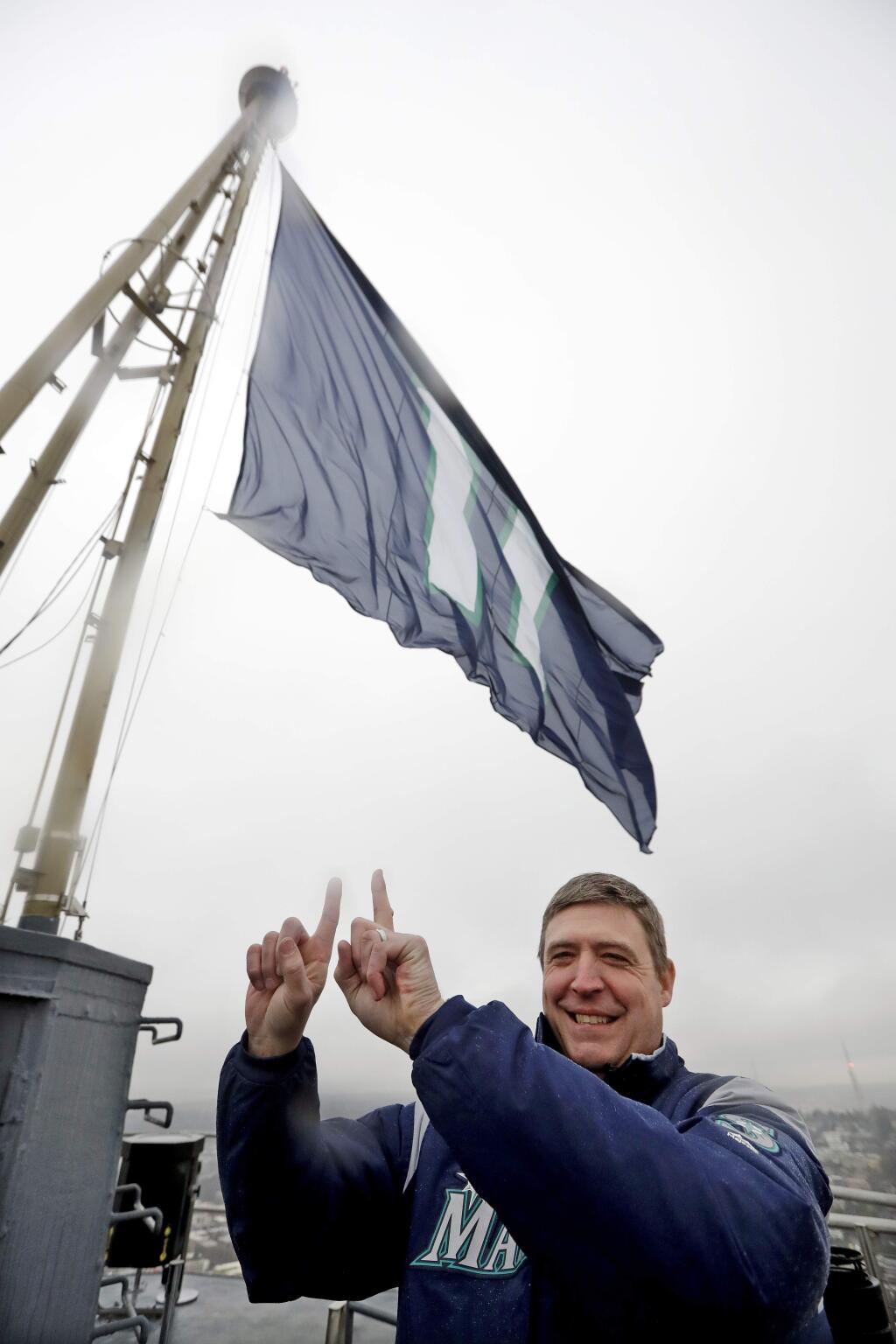 Former Seattle Mariners catcher Dan Wilson mimics the No. 11 flag behind him, honoring baseball Hall of Fame inductee Edgar Martinez with his playing number, as he poses atop the Space Needle after raising the flag Tuesday, Jan. 22, 2019, in Seattle. Martinez, the longtime Mariners' designated hitter, was elected to the Hall of Fame earlier Tuesday. (AP Photo/Elaine Thompson)