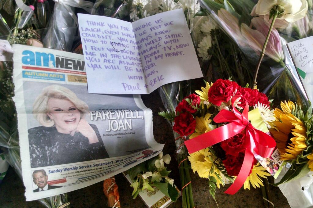 A newspaper, flowers and cards are part of a sidewalk memorial for comedian Joan Rivers at the doorstep of her apartment building, Friday, Sept. 5, 2014 in New York. Rivers died Thursday at a New York hospital following complications from surgery. She was 81. (AP Photo/Tina Fineberg)