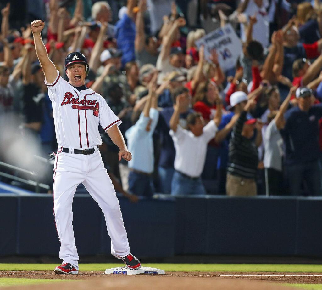 In this Sept. 25, 2012, file photo, the Atlanta Braves' Chipper Jones gestures while standing on third base after teammate Freddie Freeman hit a two-run home run to beat the Marlins 4-3 and clinch a wild-card berth for the Braves at Turner Field in Atlanta. (Curtis Compton/Atlanta Journal-Constitution via AP, File)