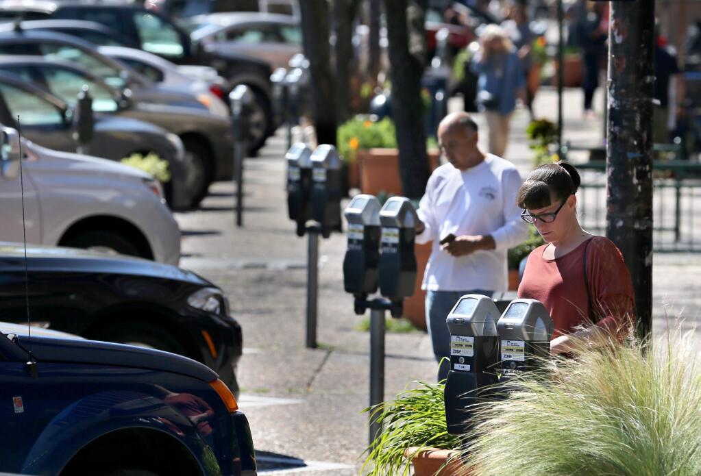 Rachel Markwardt, right, and and Tomas Cruz pay for parking at the meters on Fourth Street in Santa Rosa on Monday, March 18, 2019. (BETH SCHLANKER/ PD)
