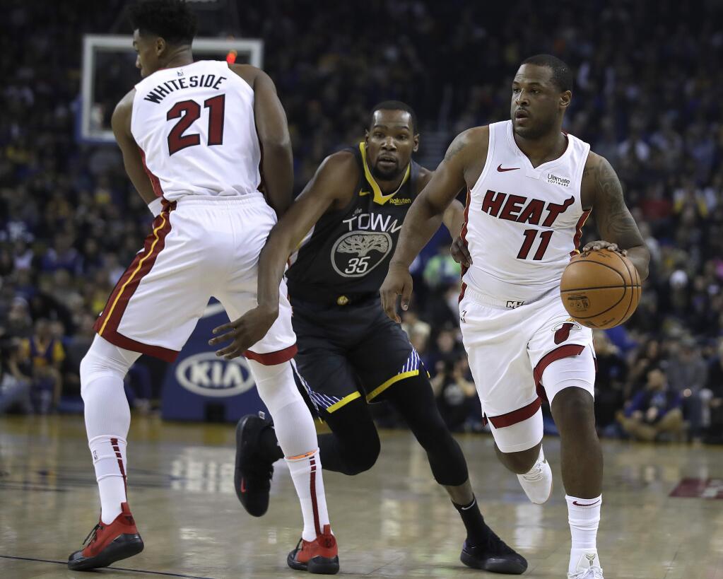 Miami Heat guard Dion Waiters, right, drives the ball as Hassan Whiteside (21) blocks Golden State Warriors' Kevin Durant, center, during the first half of an NBA basketball game day, Feb. 10, 2019, in Oakland, Calif. (AP Photo/Ben Margot)