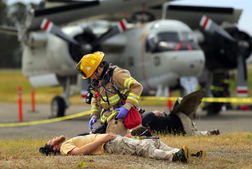 A local firefighter checks the injuries of a mock plane crash victim during a mass casualty drill at the Charles M. Schulz Sonoma County Airport on Wednesday. (photo by John Burgess/The Press Democrat)