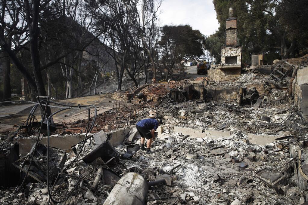 Roger Kelton searches through the remains of his mother-in-law's home leveled by the Woolsey Fire, Tuesday, Nov. 13, 2018, in the southern California city of Agoura Hills. (AP Photo/Jae C. Hong)