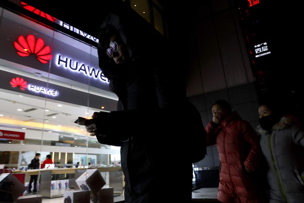 People walk past a Huawei retail shop in Beijing Thursday, Dec. 6, 2018. China on Thursday demanded Canada release a Huawei Technologies executive who was arrested in a case that adds to technology tensions with Washington and threatens to complicate trade talks. (AP Photo/Ng Han Guan)