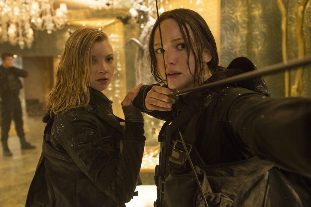 FILE - This file image released by Lionsgate shows Natalie Dormer as Cressida, left, and Jennifer Lawrence as Katniss Everdeen in a scene from 'The Hunger Games: Mockingjay Part 2.' Film and TV studio Lions Gate said Thursday, June 30, 2016, it is buying cable channel Starz in a deal worth $4.4 billion. Lions Gate is the company behind 'The Hunger Games' movies and the 'Orange Is The New Black' TV series. Englewood, Colo.-based Starz runs its namesake cable channels. Together, Lions Gate says it can tap its library of movies and TV shows and air them through Starz's channels. (Murray Close/Lionsgate via AP, File)