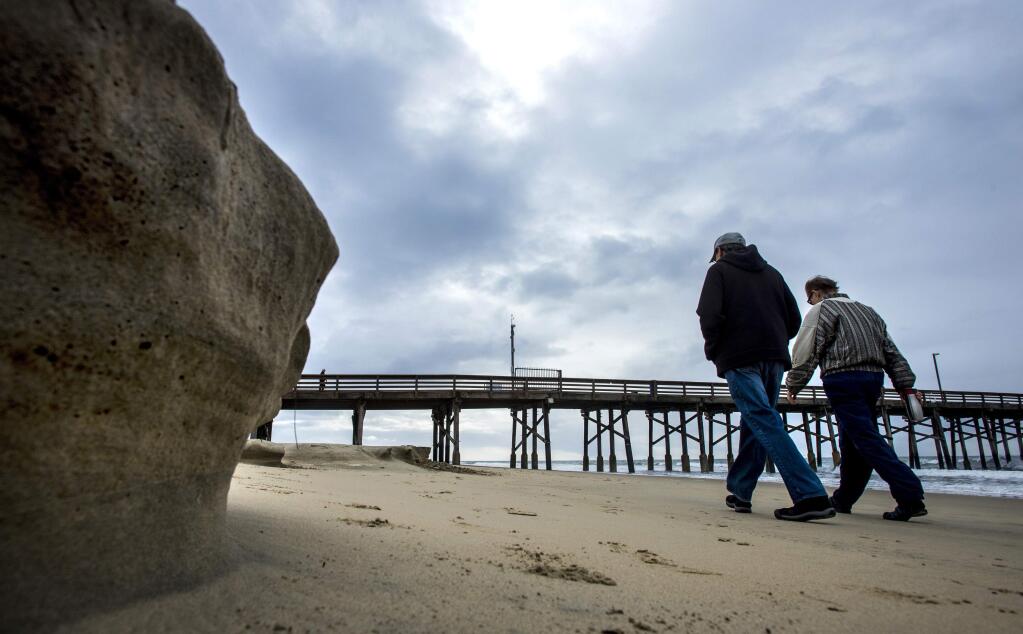 People out for a stroll make their way south near the Newport Beach Pier past some beach erosion due to in part to the recent storms and the King tide early Tuesday morning, Jan. 10, 2017, in Newport Beach, Calif. (Mark Rightmire/The Orange County Register via AP)