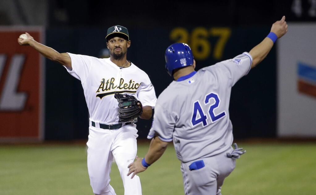 Oakland Athletics shortstop Marcus Semien, left, turns a double play over Kansas City Royals' Kendrys Morales on a ground ball by Alex Gordon during the seventh inning of a baseball game Friday, April 15, 2016, in Oakland, Calif. (AP Photo/Marcio Jose Sanchez)