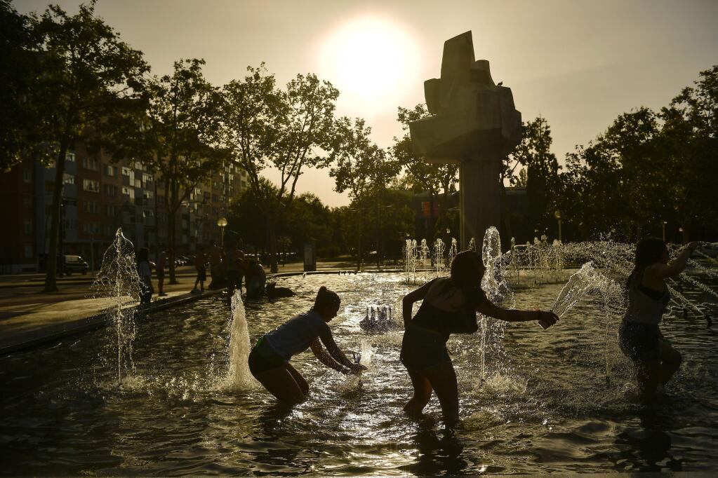 FILE - In this Saturday, Aug. 4, 2018 file photo, people cool off in a fountain during a hot summer day in the Basque city of Vitoria, northern Spain. In 2018, 29 countries and Antarctica had record hot years, says Berkeley Earth climate scientist Zeke Hausfather. (AP Photo/Alvaro Barrientos)