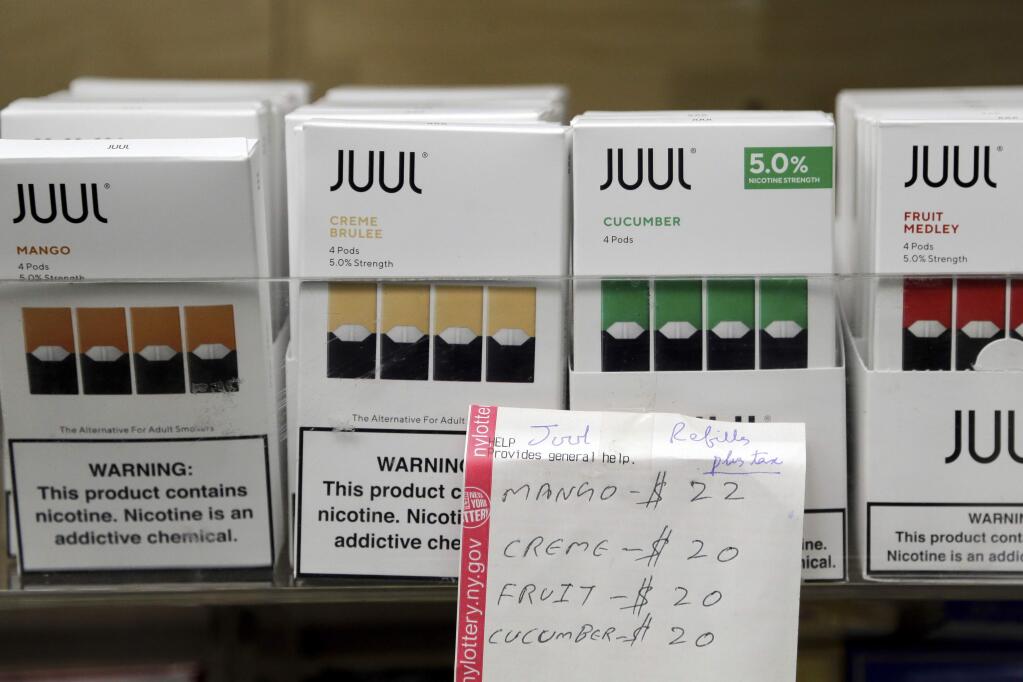 FILE - In this Thursday, Dec. 20, 2018 file photo, Juul products are displayed at a smoke shop in New York. On Thursday, Oct. 17, 2019, the company announced it will voluntarily stop selling its fruit and dessert-flavored vaping pods. (AP Photo/Seth Wenig)