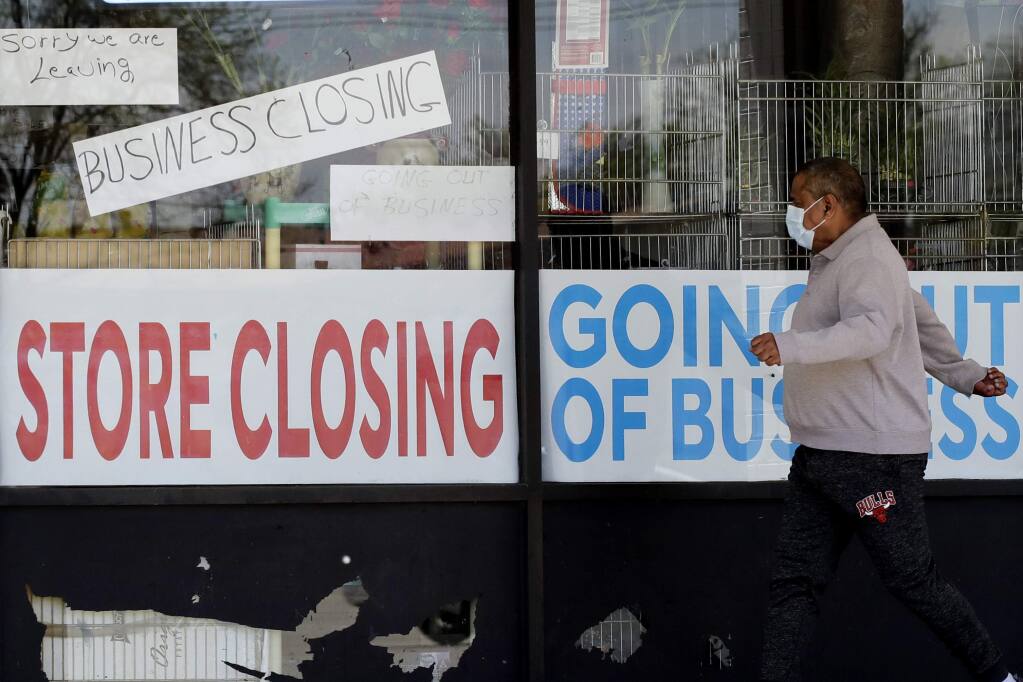 FILE - In this May 21, 2020 file photo, a man looks at signs of a closed store due to COVID-19 in Niles, Ill. In the North Bay, since November about a dozen employers filed notices of permanent and temporary job cuts. (AP Photo/Nam Y. Huh, File)