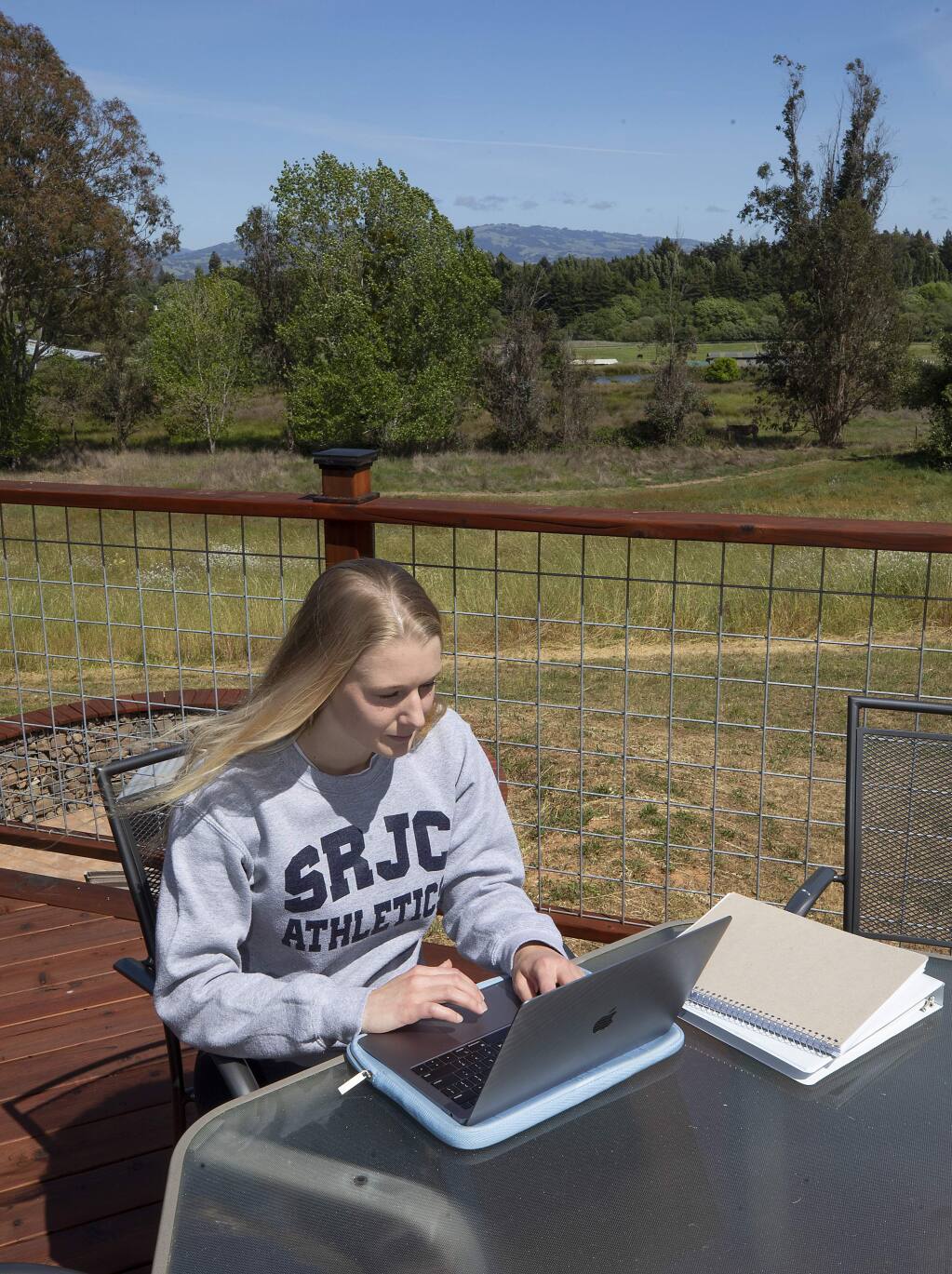 SRJC student Tallulah Kuula, who is transferring to UC Davis this fall, studies for an online biology class on the back deck of her Sebastopol home. (photo by John Burgess/The Press Democrat)