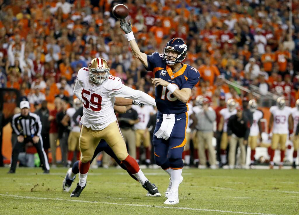 Denver Broncos quarterback Peyton Manning (18) throws his first touchdown of the game as San Francisco 49ers linebacker Aaron Lynch (59) defends during the first half of an NFL football game Sunday, Oct. 19, 2014, in Denver. (AP Photo/Jack Dempsey)