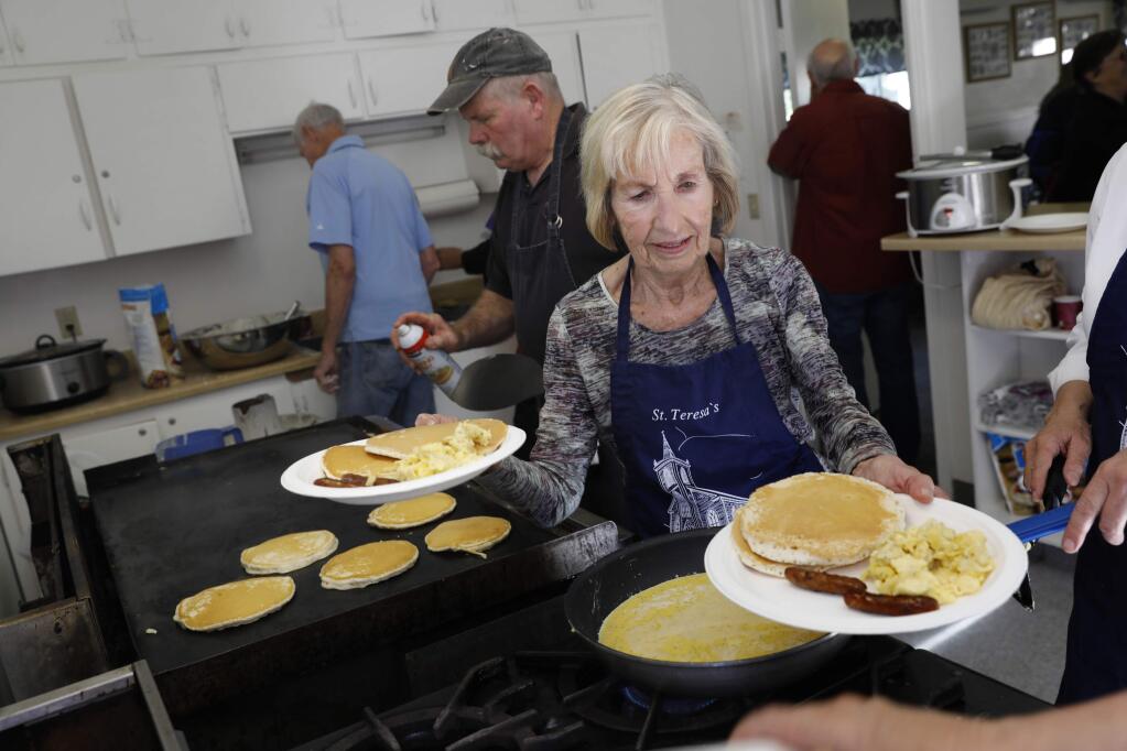 Volunteers Pat Pettibone, right, and Charlie Bone, rear, prepare plates of pancakes, eggs and sausage during a pancake breakfast to raise money for St. Teresa of Avila Church on Sunday, April 22, 2018 in Bodega, California . (BETH SCHLANKER/The Press Democrat)