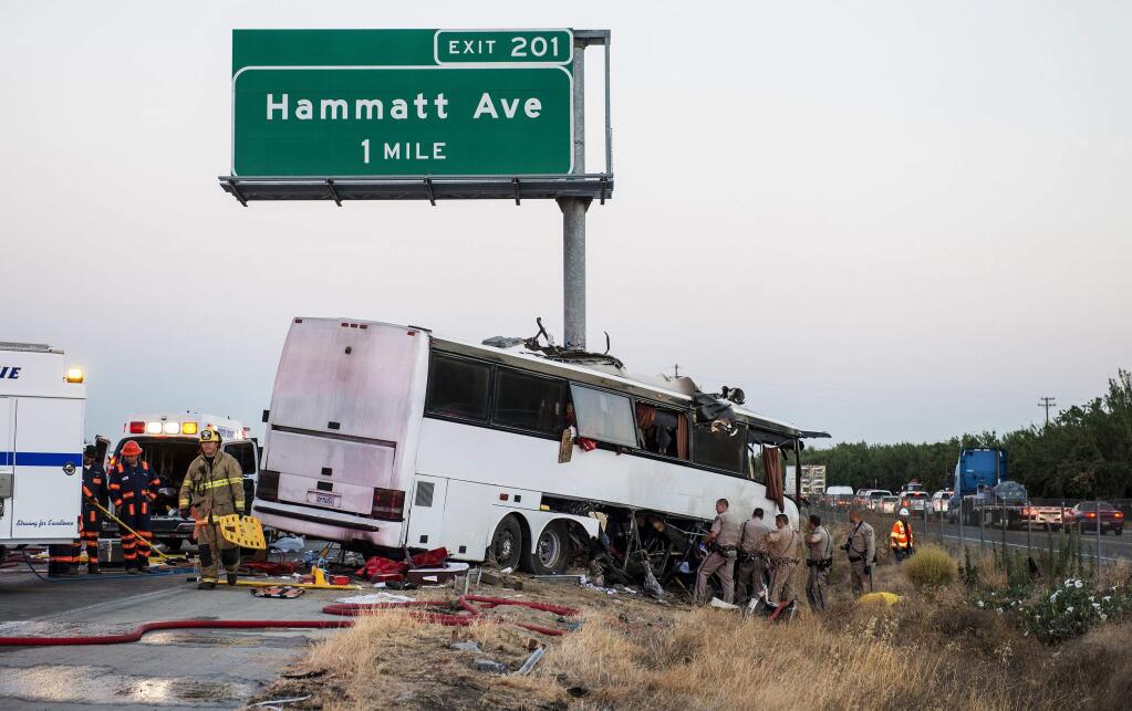 FILE - In this Aug. 2, 2016 file photo, authorities investigate the scene of a charter bus crash on northbound State Route 99 between Atwater and Livingston in California's Central Valley. In a report issues Monday, Nov. 13, 2017, the National Transportation Safety Board said a sleep-deprived driver and a bus company with a poor safety record were causes of the crash that killed four passengers and injured 20 others. The NTSB said the driver had only slept about five hours over the 40 hours preceding the crash when the bus drifted off the right side of Route 99 and struck a highway signpost that sliced the bus nearly from nose to tail. (Andrew Kuhn/Merced Sun-Star via AP, File)