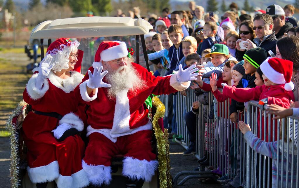 Santa and Mrs. Claus greet the crowds of kids and parents after they flew into the Pacific Coast Air Museum on Saturday in a helicopter. (photo by John Burgess/The Press Democrat)