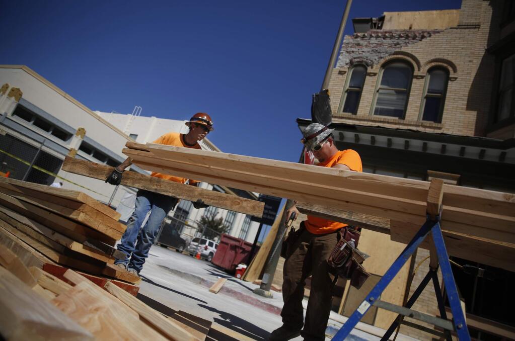 Wade Foutz, left, and Nick Stoffan, employees of Bradley Concrete, cut wood to shore up the inside of the Alexandria Square building at Second and Brown streets before the facade can be repaired on Friday, Sept. 12, 2014 in Napa. (BETH SCHLANKER / The Press Democrat)