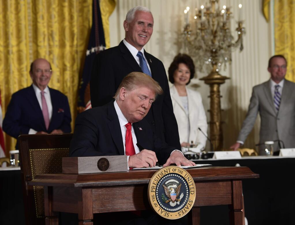 President Donald Trump signs a 'Space Policy Directive' during a meeting of the National Space Council in the East Room of the White House, Monday, June 18, 2018, in Washington, as Vice President Mike Pence looks on. AP Photo/Susan Walsh)