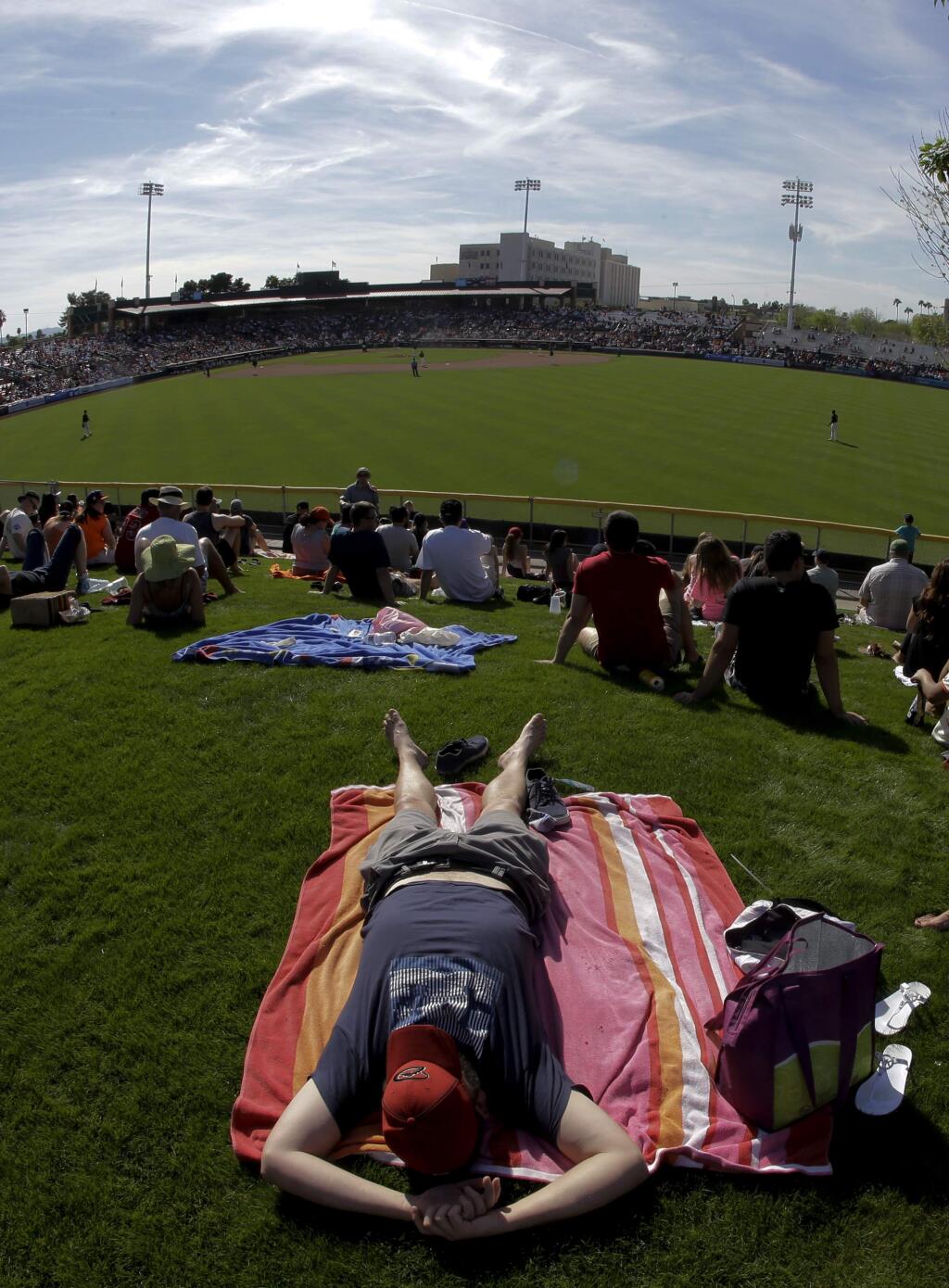 Corey Whitcher naps in the outfield sun during a spring baseball game between the San Francisco Giants and the Los Angeles Angels in Scottsdale, Ariz., Wednesday, March 2, 2016. (AP Photo/Chris Carlson)