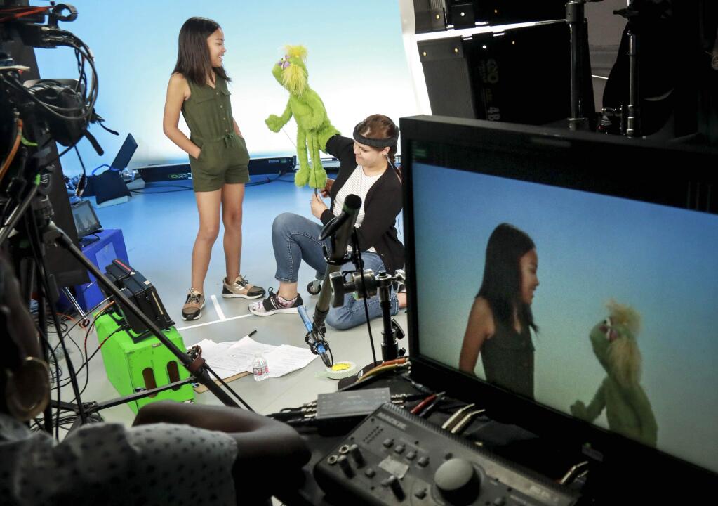 This Aug. 6, 2019 photo shows Salia Woodbury, 10, left, from Irvine, Calif., on the set with 'Sesame Street' muppet Karli and puppeteer Haley Jenkins during a taping about parental addiction in New York. Sesame Workshop is addressing the issue of addiction. Data shows 5.7 million children under 11 live in households with a parent with substance use disorder. Salia's parents are in recovery after struggling with addiction and share her experience with the show's Karli-whose muppet character has a mom who is also in recovery. (AP Photo/Bebeto Matthews)