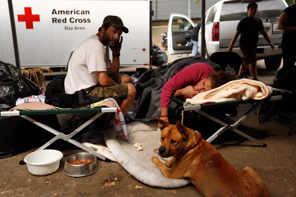 Don Potter, left and Denille Fletcher, who live in Boggs, rest on their cots with their dog Cody at the Valley Fire evacuation center at Napa County Fairgrounds in Calistoga, California on Sunday, September 13, 2015. Potter and Fletcher were evacuated from Boggs by sheriff deputies before the Valley Fire destroyed the vehicle in which they lived. (Alvin Jornada / The Press Democrat)