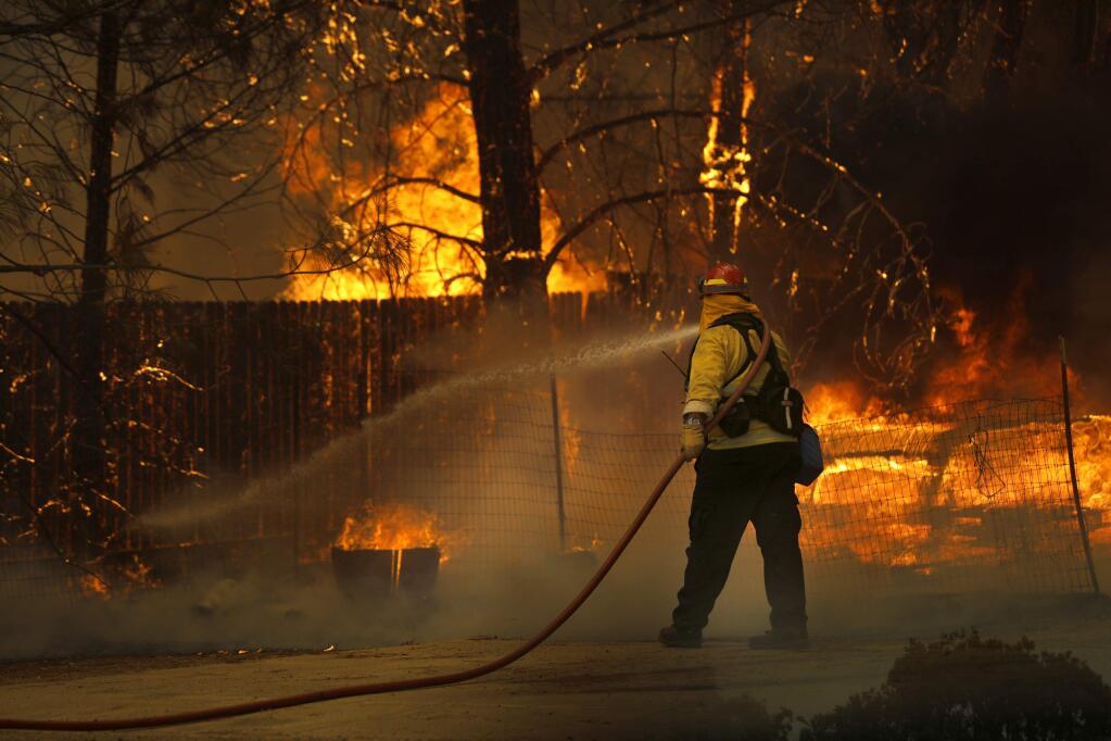 A firefighter works to put out a structure fire during the Pawnee fire on Sunday, June 24, 2018 in Spring Valley, California . (BETH SCHLANKER/The Press Democrat)