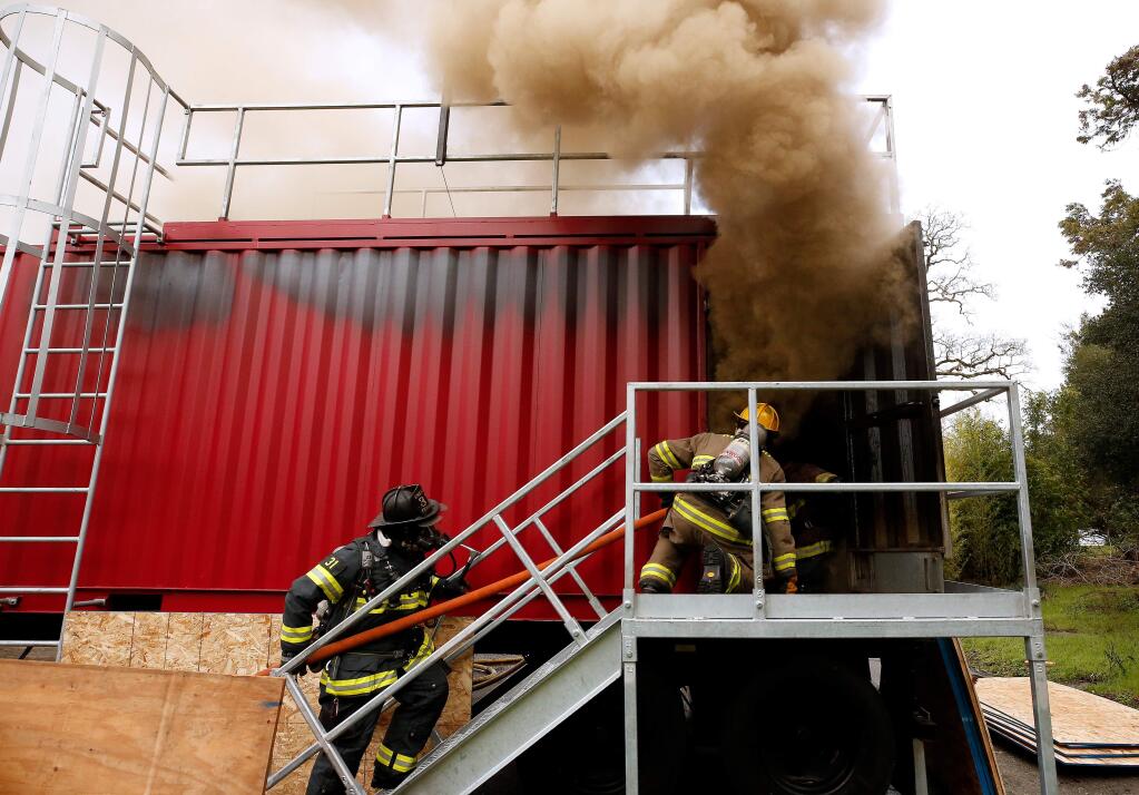 Smoke billows from the open doorway as Kenwood and Sonoma Valley firefighters advance a hoseline toward the flames inside, during a live-fire training scenario in Sonoma, California, on Saturday, January 26, 2019. (Alvin Jornada / The Press Democrat)