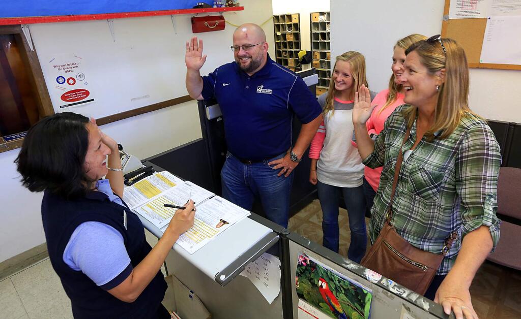 Passport Acceptance Agent Christina Rivera asks, from left to right, Jason, Molly, 15, Ivy, 14, and Anna Lea to swear their information and pictures are accurate while applying for passports at the main Santa Rosa Post Office on Friday. (JOHN BURGESS / The Press Democrat)