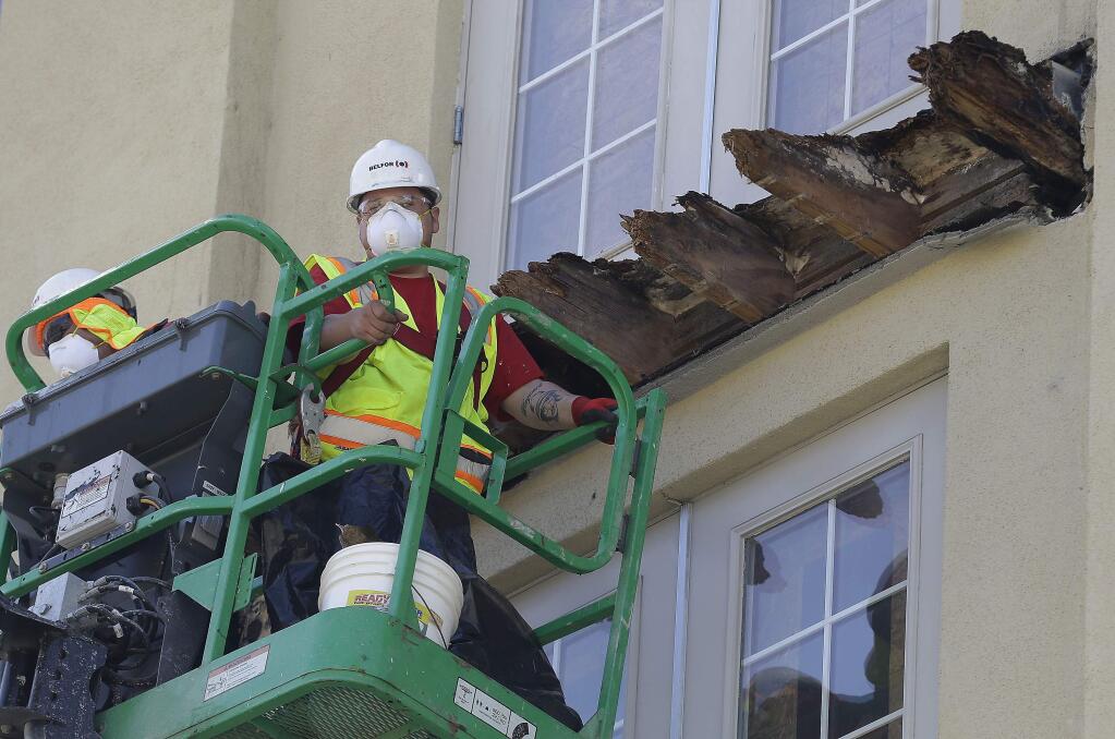 FILE - In this June 18, 2015, file photo, a crew works on the remaining wood of an apartment building balcony that collapsed in Berkeley, Calif. A balcony broke loose from an apartment building during a 21st birthday party early Tuesday, June 16, 2015, killing several and seriously injuring several others. Prosecutors in the San Francisco Bay Area say they will lead a criminal investigation into the Berkeley balcony collapse that killed six college students. The development comes after building inspectors said the fifth-floor balcony that snapped off an apartment building was supported by wooden beams badly rotted by exposure to moisture. (AP Photo/Jeff Chiu, File)