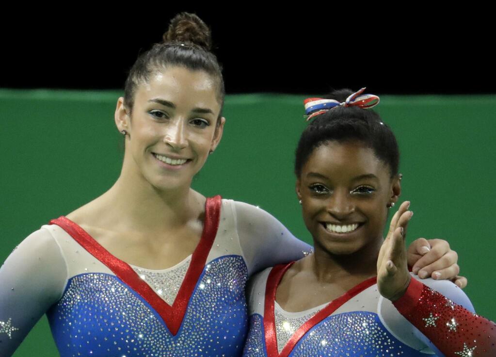 United States' Simone Biles, gold medal winner, and silver medallist and compatriot Aly Raisman, left, wave after final results for floor routine during the artistic gymnastics women's apparatus final at the 2016 Summer Olympics in Rio de Janeiro, Brazil, Tuesday, Aug. 16, 2016. (AP Photo/Dmitri Lovetsky)